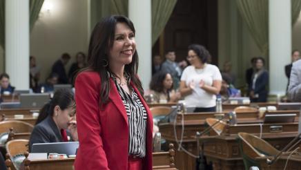 Assemblywoman Rubio smiling while standing at her desk on the Assembly Floor